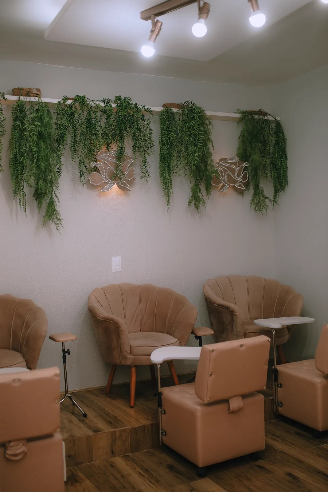 Recepção da clínica com poltronas em tom nude e plantas pendentes
